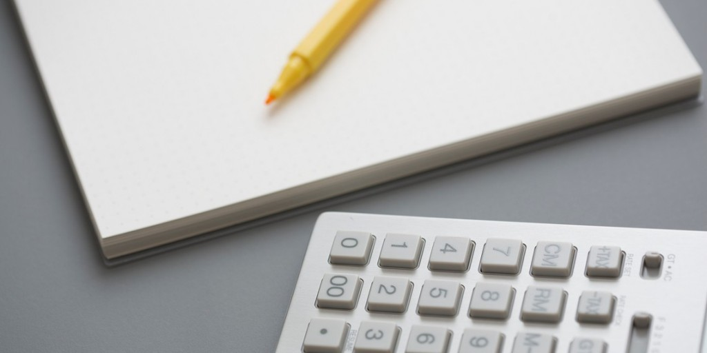 Una imagen que muestra una libreta con un lápiz encima y una calculadora al lado.